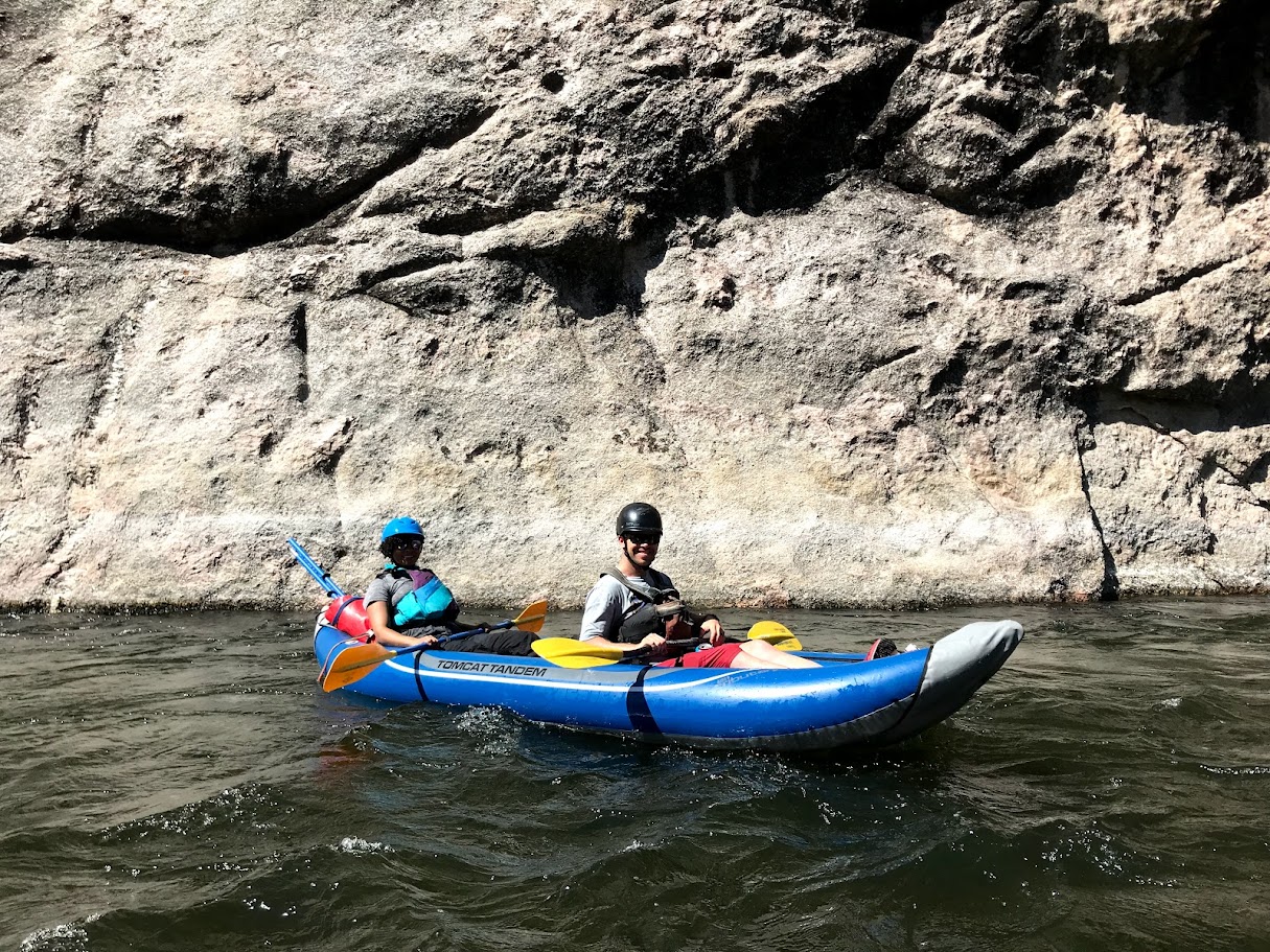 A view of two people in a inflatable kayak on the river