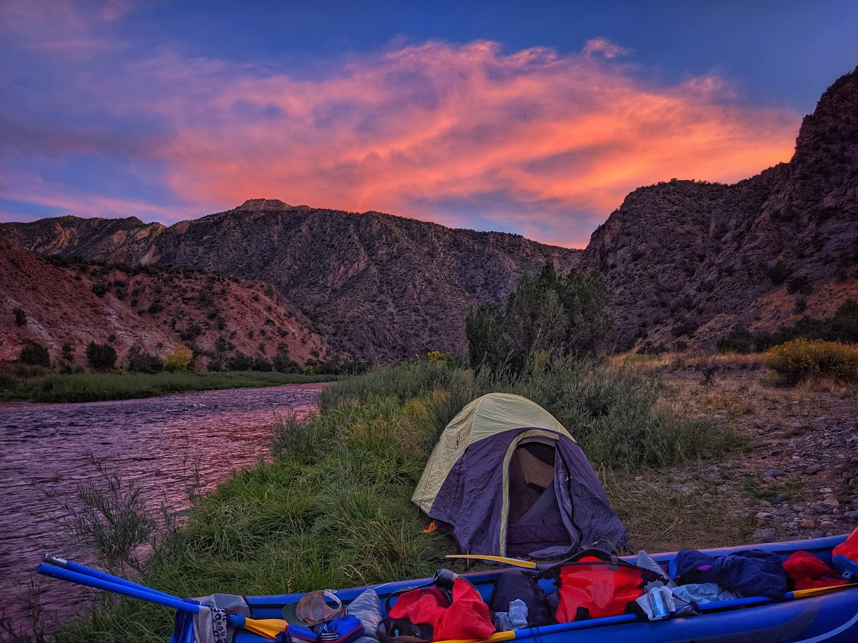A tent with a river and sunset in the background